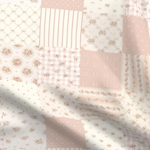 May include: A fabric featuring a patchwork design in shades of soft pink and white. The pattern consists of various squares displaying floral motifs, thin vertical stripes, small polka dots, a gingham check, and a lattice design with tiny bows.