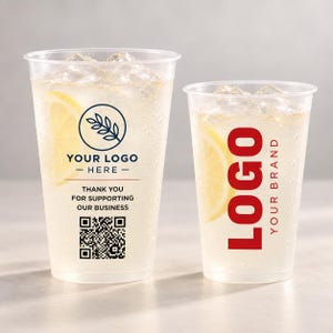 May include: Two clear plastic cups filled with a light-colored beverage, ice cubes, and a lemon slice. The left cup features a circular leaf logo, the text "YOUR LOGO HERE", "THANK YOU FOR SUPPORTING OUR BUSINESS", and a QR code. The right cup displays "LOGO YOUR BRAND" in red.