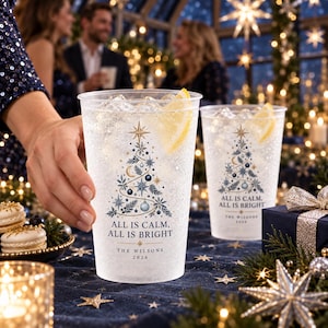 May include: Clear plastic cups featuring a printed design of a stylized Christmas tree with blue and gold ornaments, stars, and moons. The text reads "ALL IS CALM, ALL IS BRIGHT" above "THE WILSONS 2026". Each cup contains ice and a lemon wedge.