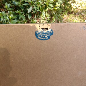 May include: The back of a brown picture frame with a blue sticker that reads "Wood Art Pictures Picture Frame Dept. Washington, D.C." and the number "13678" written in blue ink.