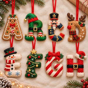 May include: A set of eight felt Christmas ornaments shaped like letters A through H. Each letter features unique holiday designs including a gingerbread man, an elf, a nutcracker, a reindeer, a snowman, a Christmas tree, a candy cane, and Santa.