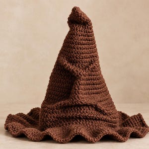以下が含まれることがあります： 高く尖った、わずかに傾いたクラウンを持つ茶色のクロッシェ編みの帽子。帽子は幅広で波打つようなつばが特徴で、ダークブラウンの生地の表面全体に目に見えるステッチが施された、糸ベースの質感のある構造になっています。