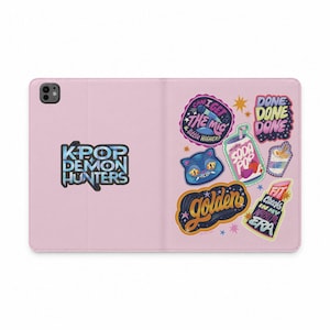 Może przedstawiać: Jasnoróżowe etui na tablet z różnorodnymi kolorowymi naklejkami. Po lewej stronie znajduje się napis KPOP DEMON HUNTERS. Po prawej stronie umieszczono naklejki z tekstami takimi jak CAN I GET THE MIC A LITTLE HIGHER, DONE DONE DONE, SODA POP, golden oraz FIT CHECK IN MY NAPALM ERA.