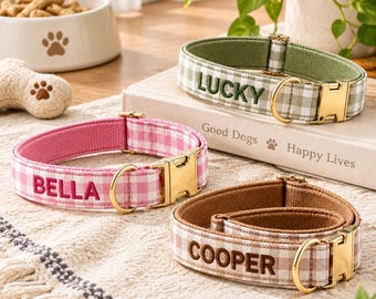 Könnte beinhalten: Drei Haustierhalsbänder aus Stoff mit goldfarbenen Metallschnallen und D-Ringen. Ein grünes Vichy-Karo-Halsband trägt den Namen LUCKY, ein rosa Modell den Namen BELLA und ein braunes den Namen COOPER, jeweils auf die Vorderseite gestickt.