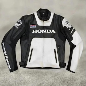 Puede incluir: Una chaqueta de moto en blanco y negro con el logotipo de Honda en el pecho, la marca HRC y el texto Honda Racing en la manga. La chaqueta incluye un cuello mao, una cremallera frontal completa y dos bolsillos con cremallera en el panel frontal.