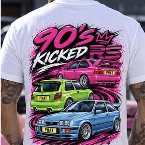 May include: A white t-shirt featuring a graphic print on the back with the text 90'S KICKED RS. The design includes three cars in pink, lime green, and light blue, each with a yellow number plate reading PHAT, set against a pink splatter.