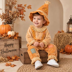 May include: A golden-yellow velvet scarecrow costume featuring a pointed hat with frayed edges, a fringed collar, and long sleeves with fringed cuffs. The outfit includes matching pants with decorative patches and frayed hems, paired with white sneakers.