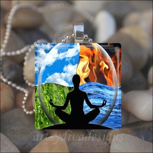 May include: A glass pendant necklace featuring a silhouette of a person meditating with four elements: blue sky, green grass, blue water, and orange fire.