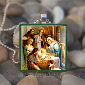 May include: A glass pendant necklace with a green border features a vintage illustration of the nativity scene. The image depicts Mary, Joseph, baby Jesus, a shepherd, and an angel. The scene is set in a stable with hay and a lamb.