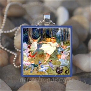 May include: A glass pendant featuring a vintage illustration of fairies dancing in a forest. The fairies are wearing white dresses and have wings. The pendant is set in a blue frame and has a silver chain.