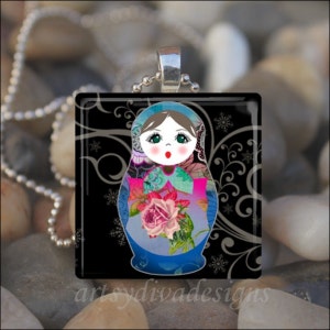 May include: A glass pendant featuring a colorful, stylized Russian nesting doll with a floral design and black and silver swirls in the background.