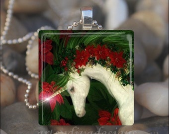 Puede incluir: Un unicornio blanco con una corona de poinsettia roja y acebo verde alrededor de la cabeza. El unicornio lleva un collar plateado con un colgante plateado. El fondo es un bosque verde.