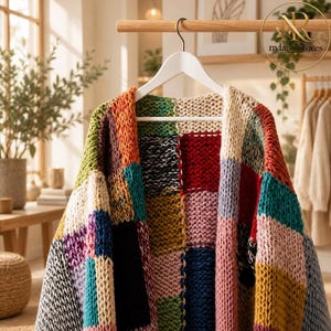 May include: A chunky knit cardigan featuring a patchwork design of multicoloured squares in shades of red, blue, green, yellow, pink, black, and cream. The garment is displayed on a white hanger and has a thick, textured yarn construction.