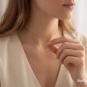 Peut inclure: Un collier doré composé d'une chaîne fine et d'un pendentif en forme de lettre S. Le pendentif présente une finition lisse et polie, suspendu à une fine chaîne en métal de couleur or assortie qui repose délicatement sur le cou.