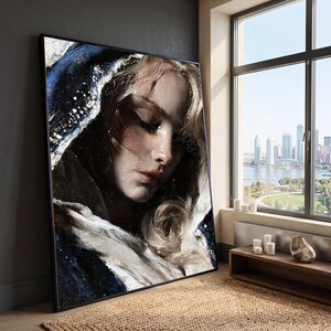 May include: A large rectangular framed wall art piece featuring a textured oil painting of a person with blonde hair and closed eyes, draped in a dark blue and white hooded garment with visible brushstrokes and a dramatic lighting effect.