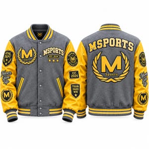 Op de afbeelding: Een grijs en geel varsity-jack met de tekst "MSPORTS" en "EST. 2024", gele "M"-logo's, lauwerkransen en "Never Give Up"-tekst op de mouwen. Het jack heeft een drukknoopsluiting aan de voorzijde en geribbelde, gestreepte boorden en een kraag.