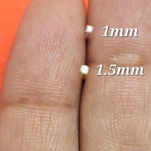 May include: Two small nose studs with clear stones, one labeled 1mm and the other labeled 1.5mm. The studs are silver-toned with prong settings. A white circular graphic with the text Best seller is visible in the upper left corner of the image.