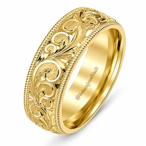 May include: A yellow gold band ring featuring an intricate engraved scrollwork pattern across the outer surface. The edges of the ring are defined by a raised beaded milgrain border. The interior of the band displays the text @VelouraJewelVault.