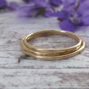 May include: Three gold rings stacked on top of each other. The rings are hammered and have a textured finish.