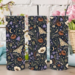 May include: Three cylindrical tumblers with a dark navy blue background featuring a repeating pattern of cream-colored moths, orange and purple wildflowers, green foliage, and small yellow crescent moons and stars, each topped with a black straw.