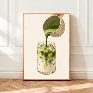 May include: A framed wall art print featuring a graphic illustration of a ceramic pitcher pouring vibrant green matcha tea into a clear glass filled with ice cubes and milk. The artwork displays a swirling blend of green tea and white milk.