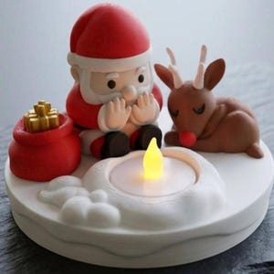 Könnte beinhalten: Ein weißer, runder Sockel mit einer skulpturalen Figur des Weihnachtsmanns im roten Anzug, einem braunen Rentier mit weißem Geweih und einem roten Geschenkesack mit goldenen Akzenten. Eine kleine, leuchtende gelbe LED-Kerze steht in der Mitte.