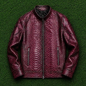 May include: A deep burgundy jacket featuring a textured snakeskin pattern throughout the exterior. The garment includes a central full-length zip, a stand-up collar, long sleeves, and two vertical zipped pockets on the front lower torso.