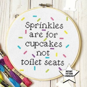 May include: A white embroidery hoop with a black cross-stitch design that reads "Sprinkles are for cupcakes not toilet seats". The hoop is surrounded by colorful sprinkles.