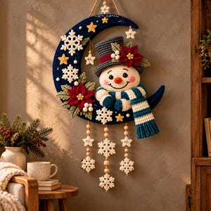 May include: A crocheted wall hanging featuring a dark blue crescent moon decorated with white snowflakes, yellow stars, red poinsettia flowers, and a snowman wearing a grey top hat and a blue and white striped scarf, with dangling snowflake ornaments.