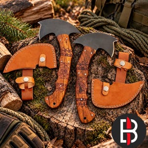 May include: Two hand axes with curved black metal blades and wooden handles featuring intricate geometric engravings. Each axe includes a tan leather sheath with a silver-colored snap button closure, designed to cover the blade edge securely.