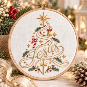 May include: A circular wooden embroidery hoop containing white fabric with a stitched design of a Christmas tree formed by the word Jesus in gold thread, accented with a gold cross, a candy cane, a bell, stars, and green pine needles.