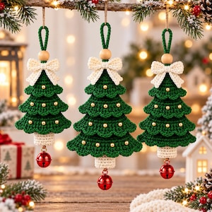 Puede incluir: Tres adornos colgantes para árbol de Navidad hechos de hilo de ganchillo verde. Cada árbol presenta un lazo de ganchillo color crema en la parte superior, una cuenta de madera, pequeñas cuentas doradas y un cascabel rojo brillante en la base.