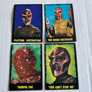 May include: Four trading cards featuring illustrations of monstrous creatures. The cards are black with white text. The text on the cards reads "Plotting Destruction", "The Brain Destroyer", "Fearful Foe", and "You Can't Stop Me".