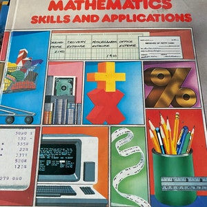 May include: A book cover with the title "Basic Mathematics Skills and Applications". The cover features colorful illustrations of a shopping cart, a calculator, a plus sign, a percentage sign, a computer, a measuring tape, and a pencil holder with pencils and pens.