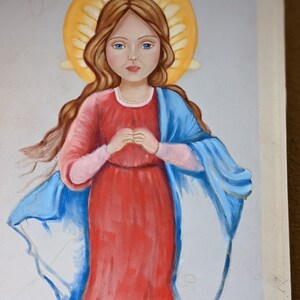 Puede incluir: Una pintura de una ni&ntilde;a joven con cabello largo y casta&ntilde;o que lleva un vestido rojo y una chal azul. Tiene un halo de luz alrededor de la cabeza y tiene las manos juntas en oraci&oacute;n.