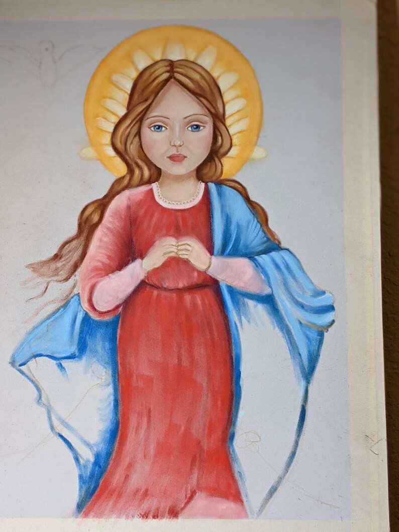 Puede incluir: Una pintura de una ni&ntilde;a joven con cabello largo y casta&ntilde;o que lleva un vestido rojo y una chal azul. Tiene un halo de luz alrededor de la cabeza y tiene las manos juntas en oraci&oacute;n.
