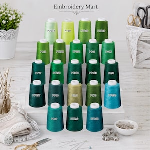 May include: A collection of twenty-five embroidery thread spools in various shades of green, arranged on a tiered white display. Each spool is labeled with a specific code, such as P7047, P120, P7049, P7369, P125, P7050, P7051, P116, P115, P117, P7250, P7370, P7103, P298, P7397, P814, P221, P173, P7090, P107, P7290, and P7185. The text Embroidery Mart is visible at the top.