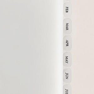 May include: A white planner or notebook page featuring a vertical row of translucent, rounded tabs along the right edge. Each tab is labeled with black, capitalized text representing the months of the year, starting with JAN, FEB, MAR, APR, MAY, JUN, JUL, and AU.