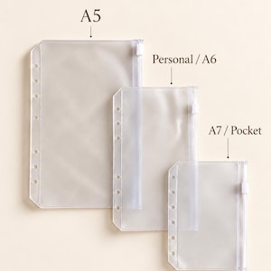 May include: Three clear plastic zipper pouches with punched holes for ring binders, labeled A5, Personal / A6, and A7 / Pocket. Each pouch features a white zipper pull and a vertical row of circular holes along the left side for secure attachment.