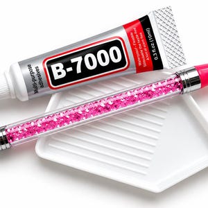 May include: A 0.3 fl. oz. tube of B-7000 multi-purpose adhesive, a clear pen-style applicator filled with small pink crystals, and a white plastic grooved tray. The adhesive tube features a silver, red, and black label with white text.