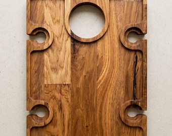 May include: A rectangular wooden serving board featuring a natural brown grain pattern. The board includes a circular cutout at the top center and four semi-circular notches along the side edges, designed to hold items securely in place.