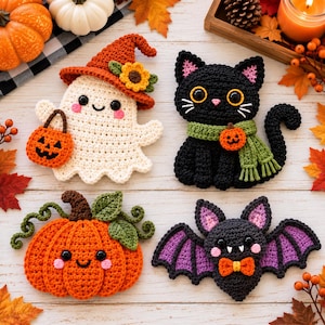 Peut inclure: Quatre décorations d'Halloween au crochet : un fantôme blanc portant un chapeau orange avec un tournesol, un chat noir avec une écharpe verte et une breloque citrouille, une citrouille orange avec des feuilles vertes et une chauve-souris gris foncé.