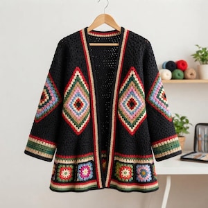 Könnte beinhalten: Eine schwarze Häkelstrickjacke mit großen rautenförmigen Motiven auf den Vorderteilen und Ärmeln, akzentuiert durch mehrfarbiges Garn in Rosa, Blau, Grün und Gelb. Der Saum und die Ärmelbündchen sind mit einem bunten quadratischen Muster versehen.
