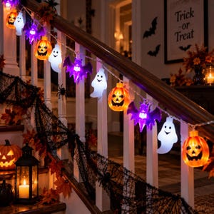 Könnte beinhalten: Eine Halloween-Lichterkette mit abwechselnden orangefarbenen Kürbissen, weißen Geistern und violetten Fledermäusen. Die beleuchteten Figuren sind durch einen dünnen Draht verbunden und entlang eines Treppengeländers aus Holz drapiert.