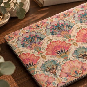 Könnte beinhalten: Eine Laptop-Hülle mit einem sich wiederholenden Muster aus fächerförmigen Blumenmotiven in Rosa-, Türkis- und Goldtönen auf cremefarbenem Grund. Das Design bedeckt die flache, rechteckige Oberfläche des geschlossenen Laptops.