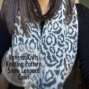 May include: A woman wearing a gray and white knitted cowl with a snow leopard pattern. The cowl is a circular scarf that is worn around the neck. The text "VanessaKnits Knitting Pattern Snow Leopard Cowl" is superimposed on the image.
