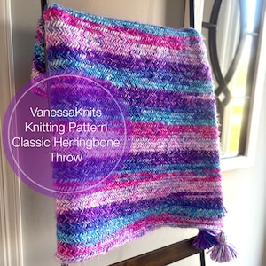 May include: A colorful knitted throw blanket with a herringbone pattern and tassels. The blanket is made with a variety of shades of purple, pink, and blue yarn. The text "VanessaKnits Knitting Pattern Classic Herringbone Throw" is visible on the blanket.