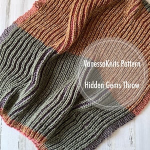May include: A knitted throw blanket in shades of green, brown, and pink. The blanket is made with a textured stitch and has a striped pattern. The text "VanessaKnits Pattern Hidden Gems Throw" is visible in the image.