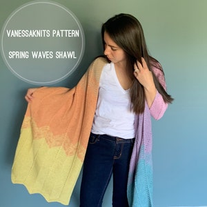 May include: A woman wearing a white shirt and blue jeans is wearing a colorful crocheted shawl. The shawl is a gradient of yellow, orange, and purple. The text "VANESSSAKNITS PATTERN SPRING WAVES SHAWL" is visible in a circle in the upper left corner of the image.