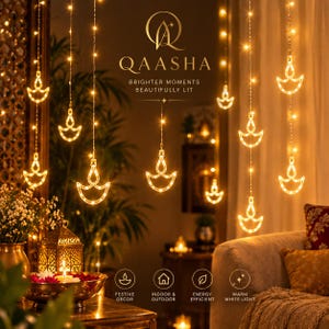 May include: A string of LED lights featuring hanging diya-shaped ornaments that emit a warm white glow. The text QAASHA BRIGHTER MOMENTS BEAUTIFULLY LIT is visible, along with icons for festive decor, indoor and outdoor use, energy efficiency, and warm light.